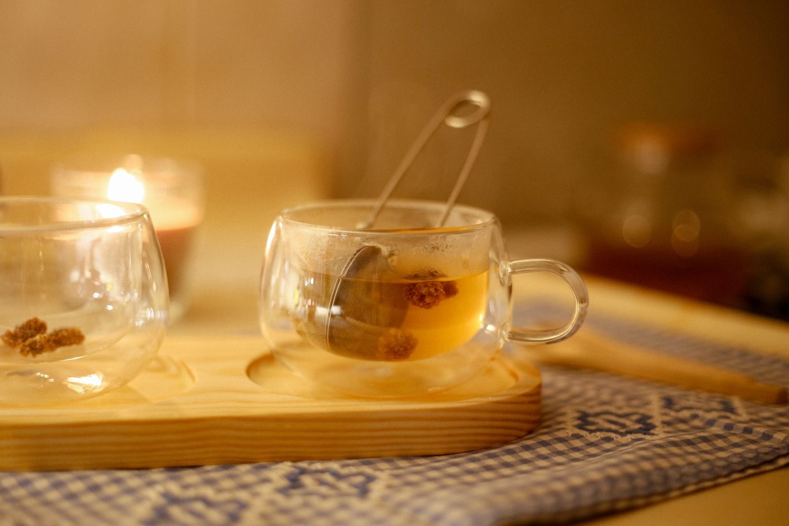 Warm and cozy herbal tea setup with glass cups and candlelight, perfect for relaxation.
